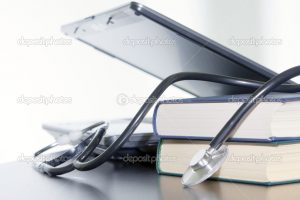 Laptop, books and medical stethoscope on the table.
