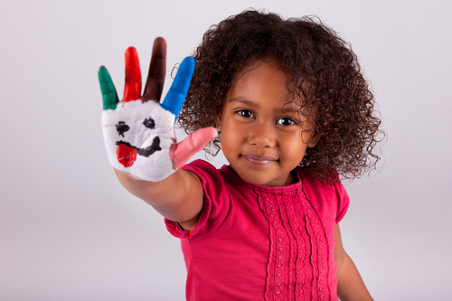Little African Asian girl with painted hands in colorful paints