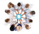 Medical Team Joining Jigsaw Pieces While Standing In Huddle