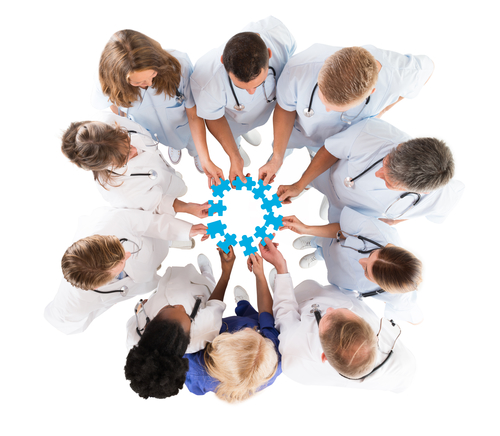 Directly above shot of medical team joining blue jigsaw pieces against white background